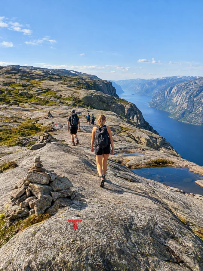 Randonneurs traversant le granit lisse du plateau du Kjerag au-dessus du Lysefjord