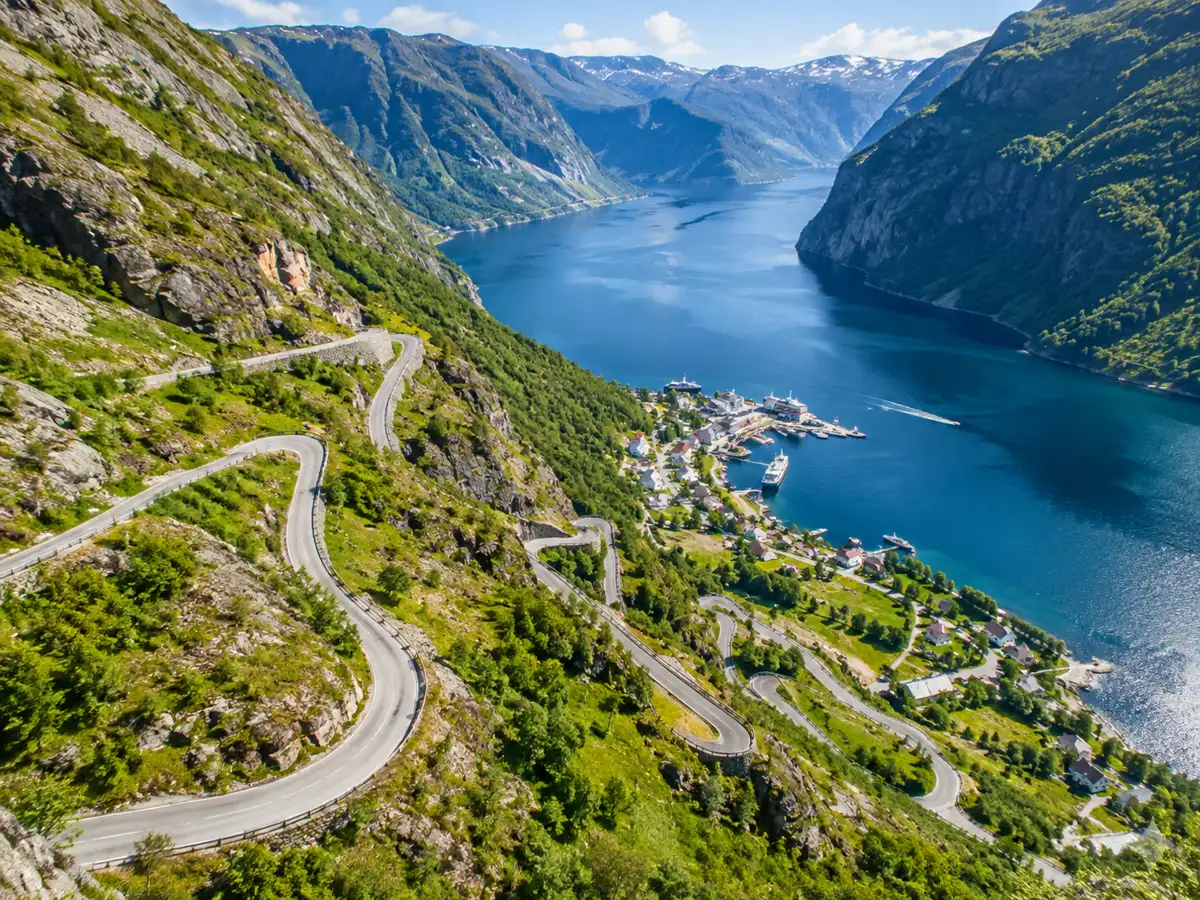 Une route de montagne aux virages en épingle serrés descendant vers le fond d'un fjord norvégien