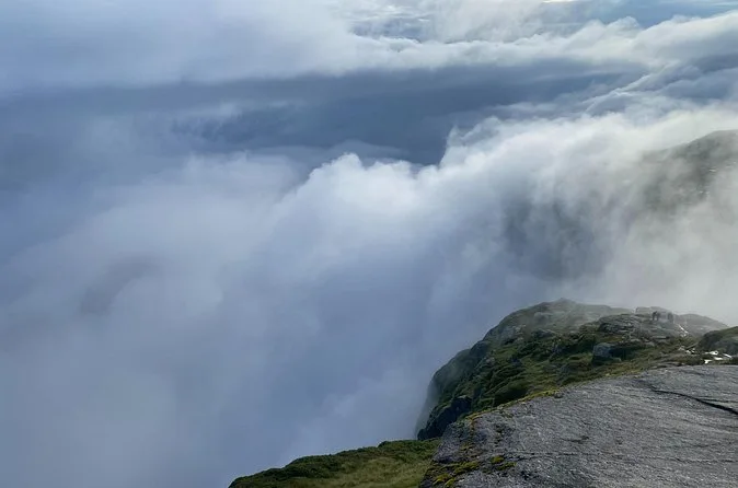 Thick cloud pouring over the edge of a granite cliff, with only the rock in the foreground visible